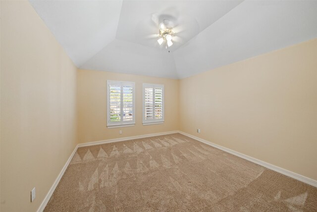 spare room with ceiling fan, light colored carpet, baseboards, and lofted ceiling