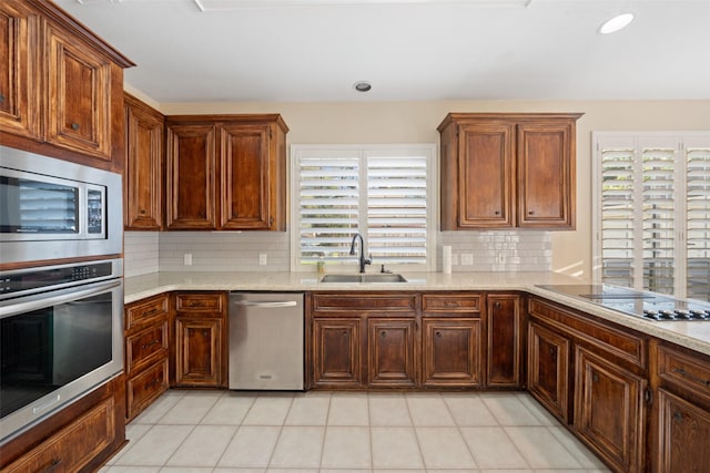 kitchen with a sink, appliances with stainless steel finishes, light tile patterned floors, and tasteful backsplash