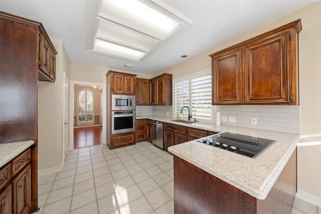 kitchen featuring decorative backsplash, a peninsula, light countertops, a sink, and appliances with stainless steel finishes