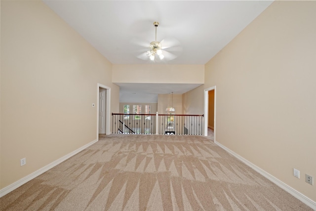 carpeted spare room with baseboards and ceiling fan with notable chandelier
