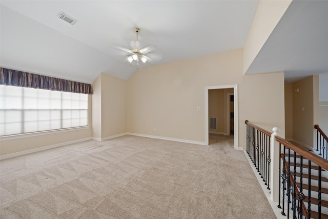 spare room with visible vents, a ceiling fan, vaulted ceiling, and light colored carpet