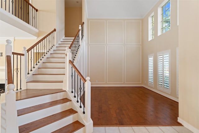 stairs with wood finished floors, baseboards, and a high ceiling