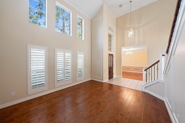 entryway with high vaulted ceiling, baseboards, hardwood / wood-style flooring, and a notable chandelier