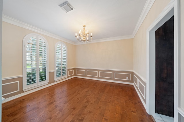 spare room with a decorative wall, hardwood / wood-style flooring, and visible vents