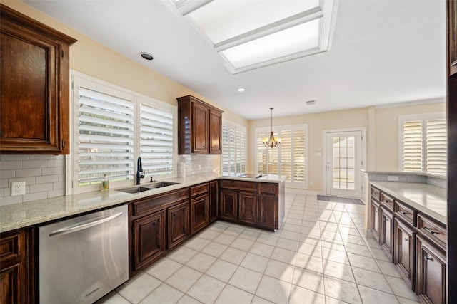 kitchen with a healthy amount of sunlight, backsplash, dishwasher, a sink, and a notable chandelier