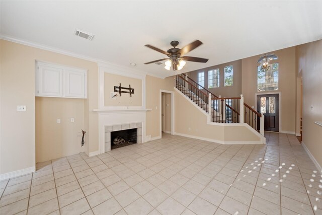 unfurnished living room with visible vents, stairway, a tile fireplace, a ceiling fan, and light tile patterned floors
