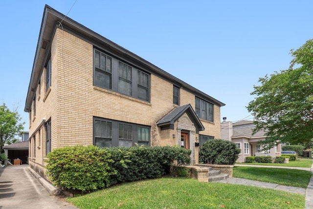 view of property featuring brick siding and a front lawn