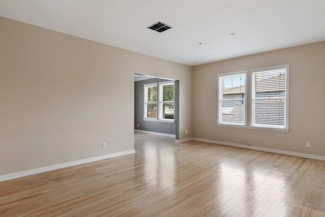 spare room featuring visible vents, light wood-style flooring, and baseboards