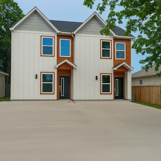view of front of property with fence, board and batten siding, a patio area, and central AC