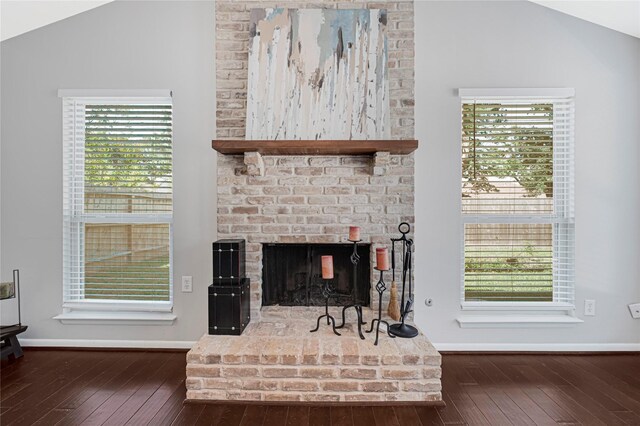 living room featuring baseboards, wood-type flooring, a brick fireplace, and lofted ceiling