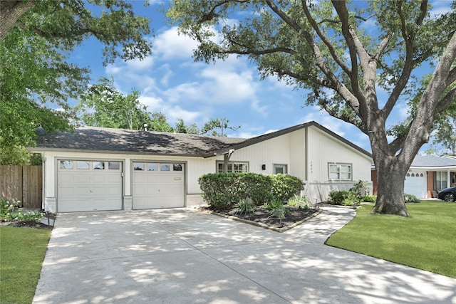 view of front of house featuring fence, an attached garage, driveway, and a front lawn