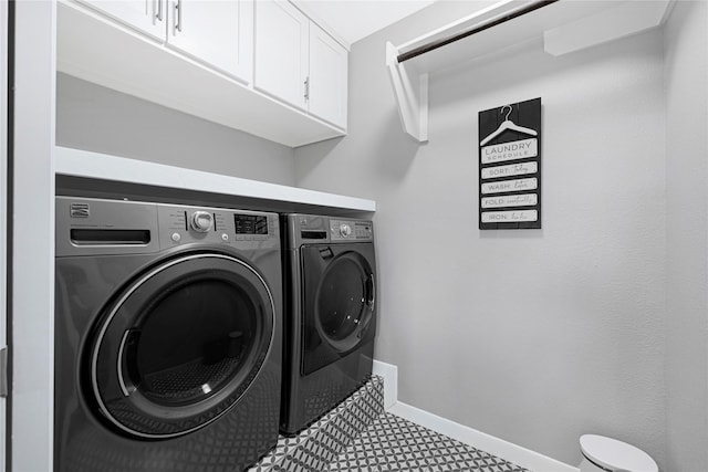clothes washing area with baseboards, cabinet space, and washing machine and clothes dryer
