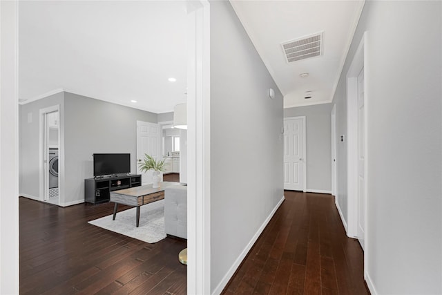 hallway with washer / clothes dryer, baseboards, visible vents, and hardwood / wood-style flooring
