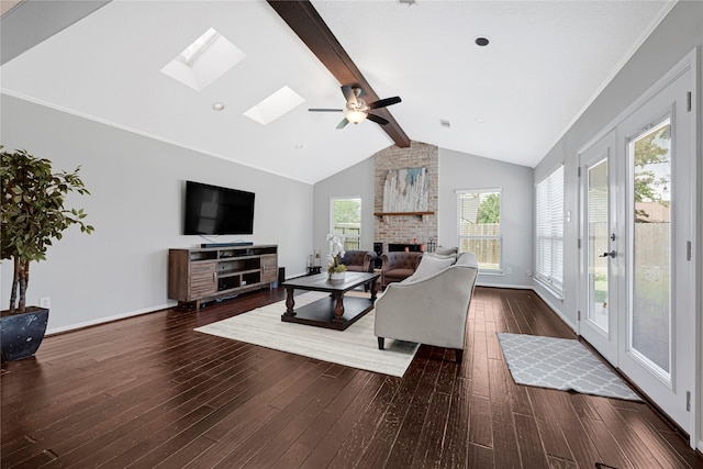 living area with a brick fireplace, a ceiling fan, baseboards, lofted ceiling with skylight, and hardwood / wood-style flooring