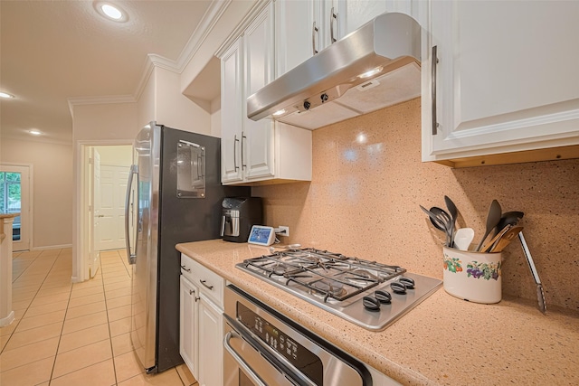 kitchen with crown molding, light tile patterned flooring, under cabinet range hood, stainless steel appliances, and white cabinetry