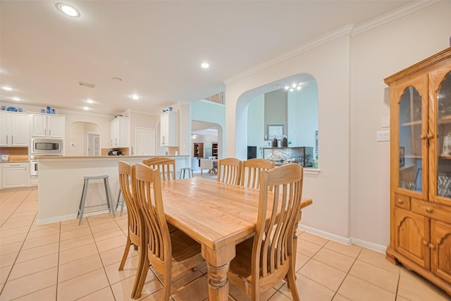 dining space featuring crown molding, arched walkways, recessed lighting, and light tile patterned floors