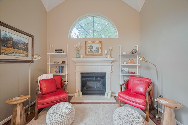 living area with a glass covered fireplace, baseboards, carpet, and lofted ceiling