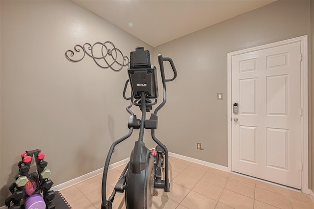 exercise area featuring baseboards, light tile patterned floors, and vaulted ceiling