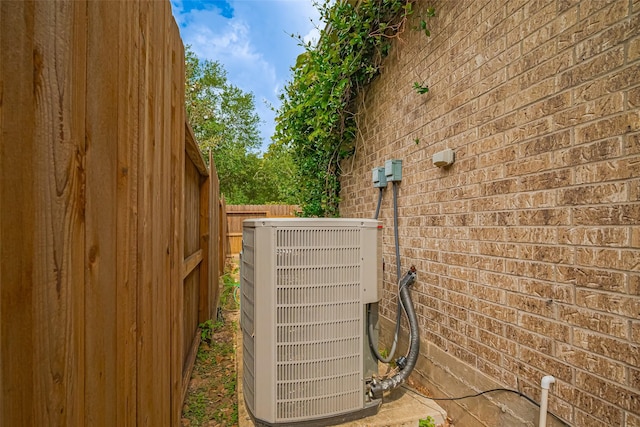 exterior details featuring central air condition unit, fence, and brick siding
