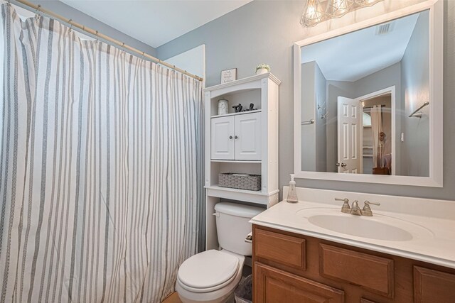 bathroom with vanity, toilet, curtained shower, and visible vents