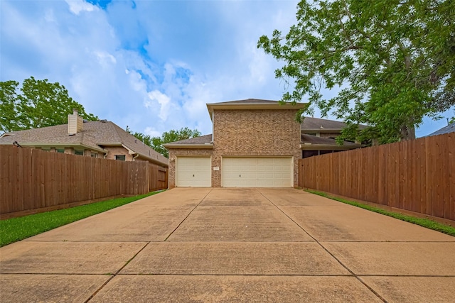 view of side of property featuring fence, an attached garage, concrete driveway, and brick siding