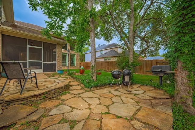 view of patio featuring a fenced backyard, a sunroom, and a grill