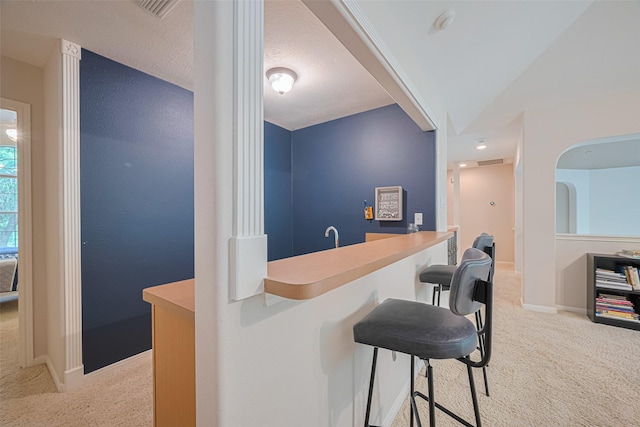 bar featuring indoor wet bar, baseboards, light colored carpet, and visible vents