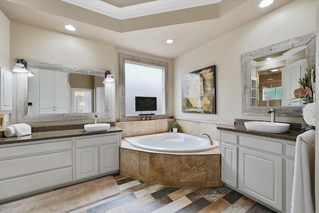 full bath featuring crown molding, a sink, a bath, and two vanities