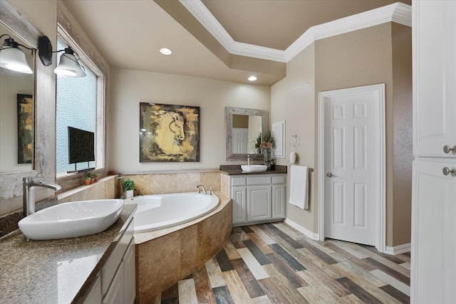 bathroom with a sink, ornamental molding, a garden tub, and two vanities