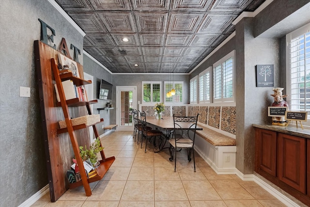 dining space featuring plenty of natural light, an ornate ceiling, a textured wall, and light tile patterned flooring