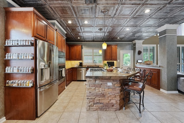 kitchen featuring a sink, an ornate ceiling, brown cabinetry, stainless steel appliances, and ornate columns