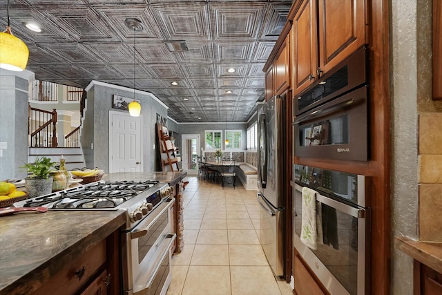 kitchen with brown cabinetry, pendant lighting, an ornate ceiling, appliances with stainless steel finishes, and light tile patterned floors