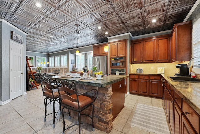 kitchen with an ornate ceiling, stainless steel appliances, light tile patterned floors, and a sink