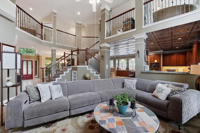 living area with ornate columns, recessed lighting, a towering ceiling, and stairway