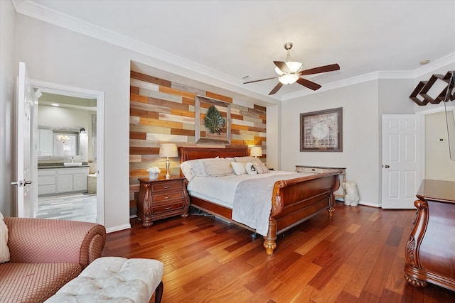 bedroom with baseboards, ornamental molding, ensuite bath, and wood finished floors