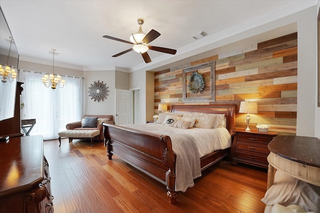 bedroom with visible vents, crown molding, dark wood-style flooring, wooden walls, and ceiling fan with notable chandelier