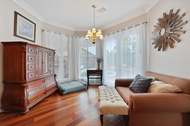 living area with visible vents, ornamental molding, wood finished floors, and a chandelier