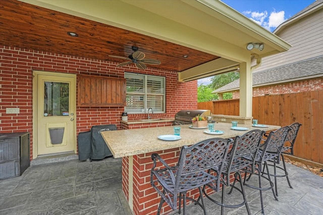 view of patio with ceiling fan, fence, a sink, area for grilling, and outdoor wet bar