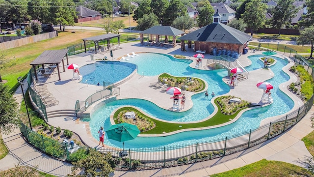 community pool featuring a gazebo, a water play area, and fence