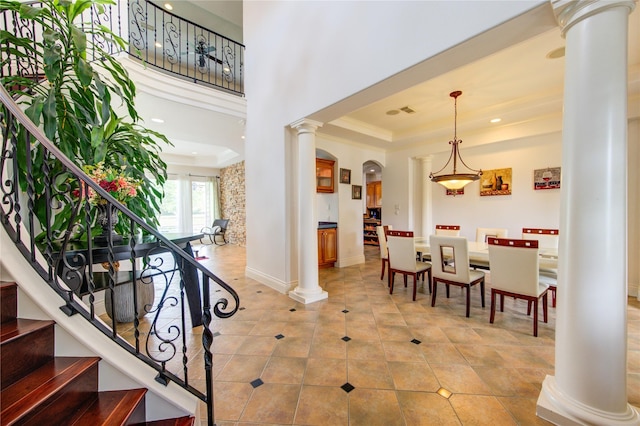 foyer with decorative columns, light tile patterned floors, baseboards, stairway, and a tray ceiling