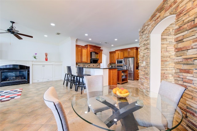 dining space featuring ceiling fan, a tile fireplace, ornamental molding, recessed lighting, and light tile patterned flooring