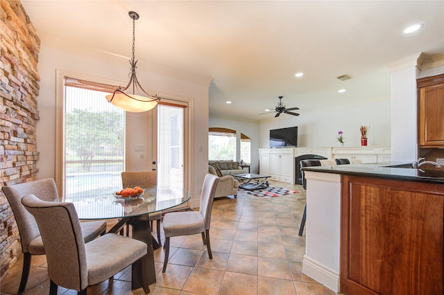 dining room with crown molding, a ceiling fan, arched walkways, and a fireplace
