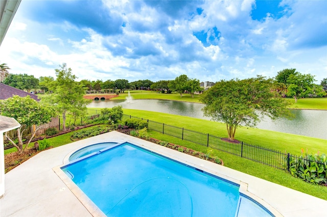 view of swimming pool with fence, a water view, a yard, and a pool with connected hot tub