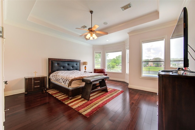 bedroom with visible vents, baseboards, a tray ceiling, and dark wood-style floors