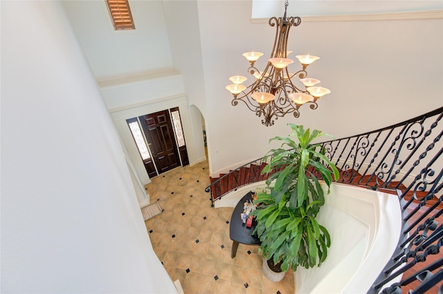 entryway featuring visible vents, stairs, a towering ceiling, a chandelier, and arched walkways