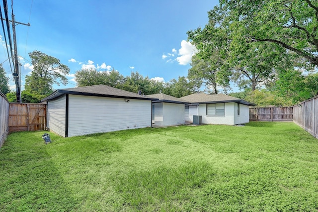 back of property featuring a lawn, central AC unit, and a fenced backyard