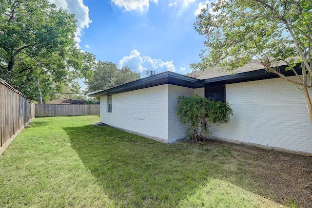 view of side of home with a lawn, brick siding, and a fenced backyard