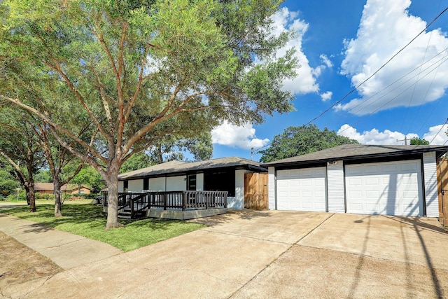 ranch-style home with an outdoor structure, concrete driveway, a porch, and a front yard