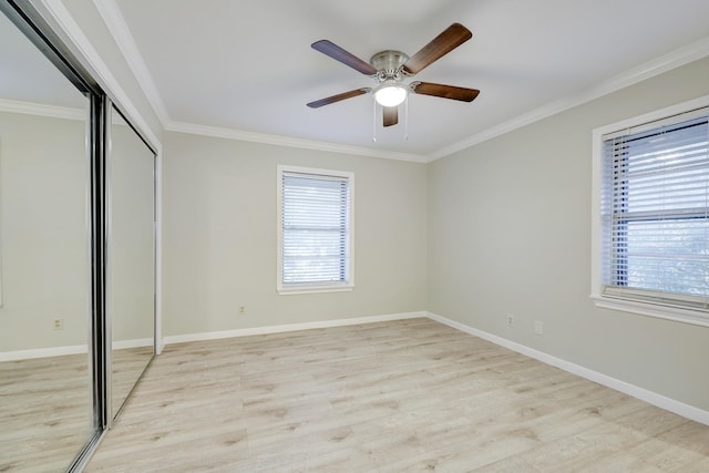 unfurnished bedroom featuring light wood-style floors, ornamental molding, baseboards, and a closet