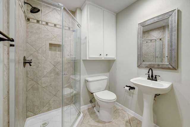 bathroom with toilet, tile patterned floors, a shower stall, and baseboards
